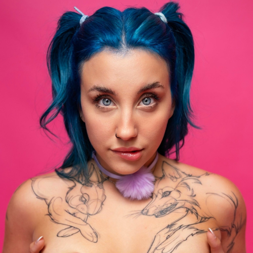 Xoklautease, modelo de OnlyFans nude, con cabello azul y tatuajes llamativos en fondo rosa.