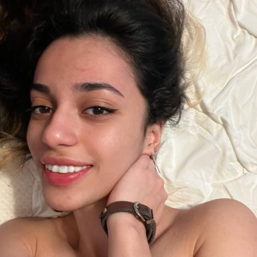 Smile2003, famosa creadora en modelo de OnlyFans, posando con una sonrisa natural y relajada en la cama.